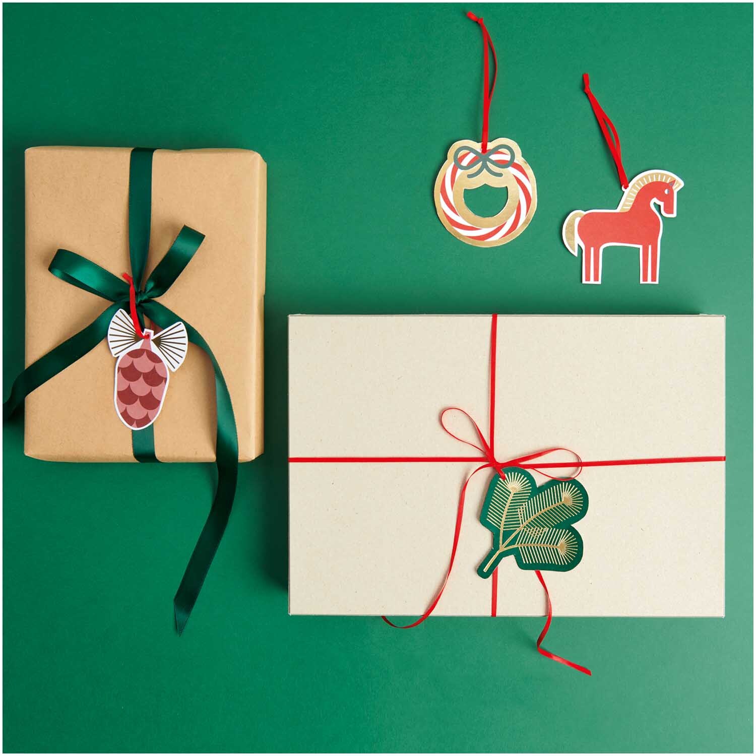 Paper Poetry Geschenkanhänger Christmas Rocks! 8 Stück von Rico Design Paper Poetry Geschenkanhänger Christmas Rocks! 8 Stück von Rico Design, dekoriert auf Geschenken mit roten und grünen Bändern auf grünem Hintergrund.