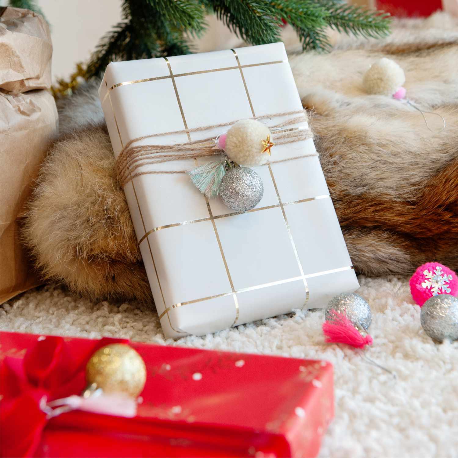Pompon- und Kugel-Anhänger neon-pastell 6 Stück von Rico Design Pompon- und Kugel-Anhänger neon-pastell 6 Stück dekorieren ein Geschenk mit festlichem Flair vor einem Weihnachtsbaum.