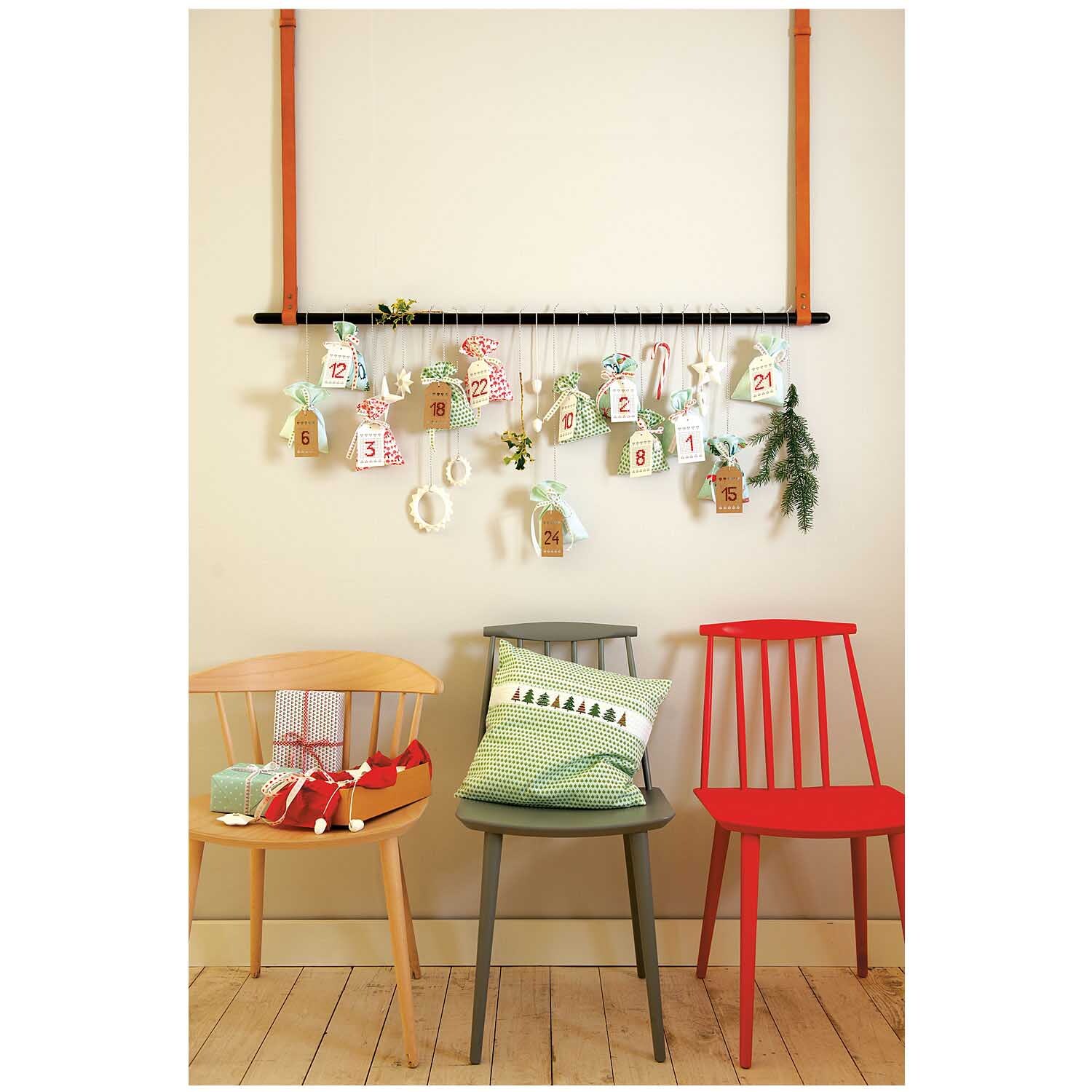 Paper Poetry Adventskalender Anhänger aus Kraftpapier in Braun, dekorativ an einer Wand hängend, mit drei bunten Stühlen darunter.