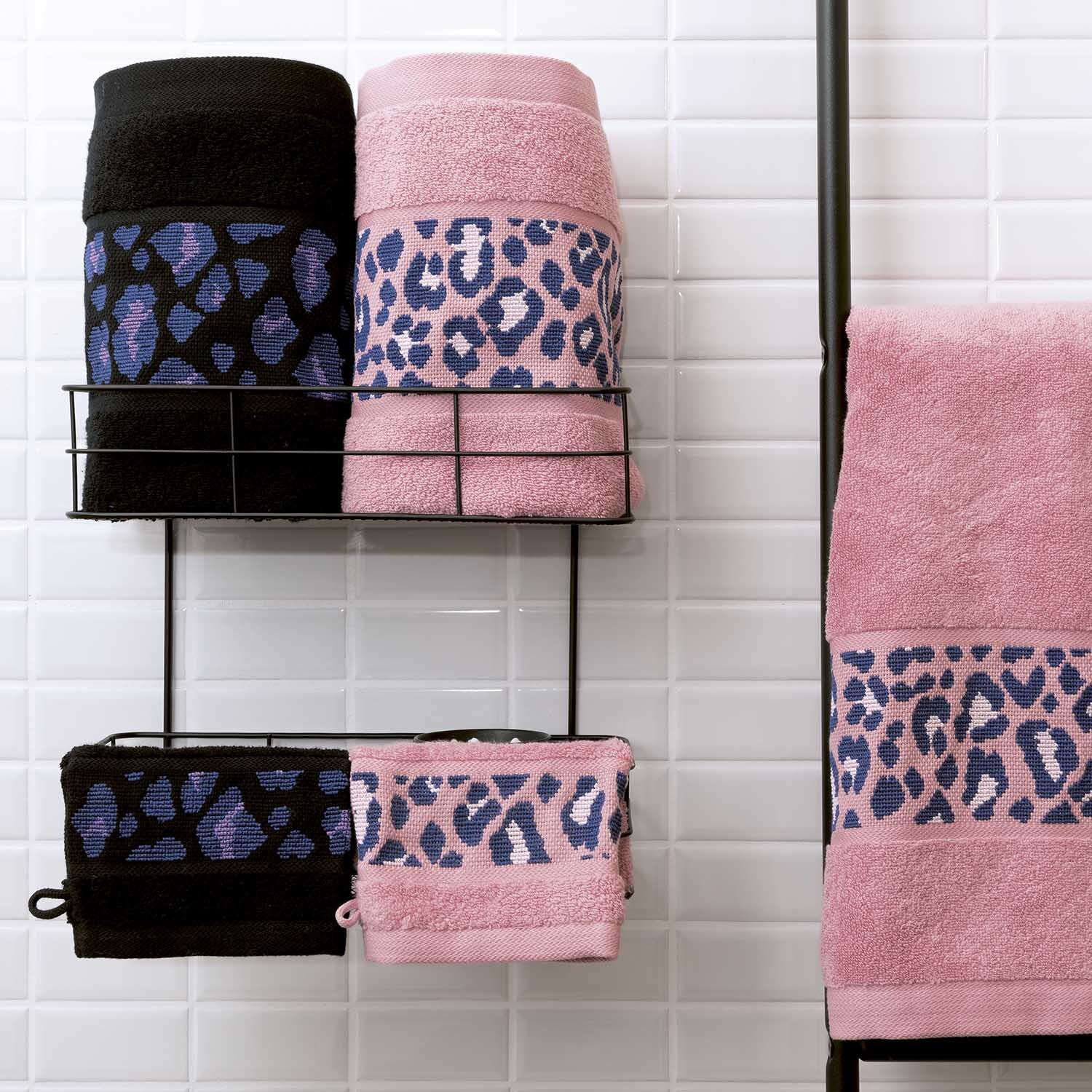 Serviette de bain 50x100cm Couleur Noir from Rico Design Handtuch 50x100cm mit Leopardenmuster in Schwarz und Rosa, präsentiert auf einem Handtuchhalter vor weißen Fliesen. Ideal für stilvolle Badezimmer.