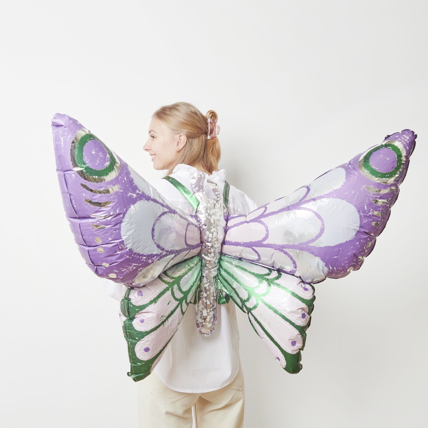 Folienballon Schmetterling zum Umbinden Lila/Grün 110x73cm von Rico Design Folienballon Schmetterling zum Umbinden in Lila-Grün von Rico Design, getragen von einer Person.