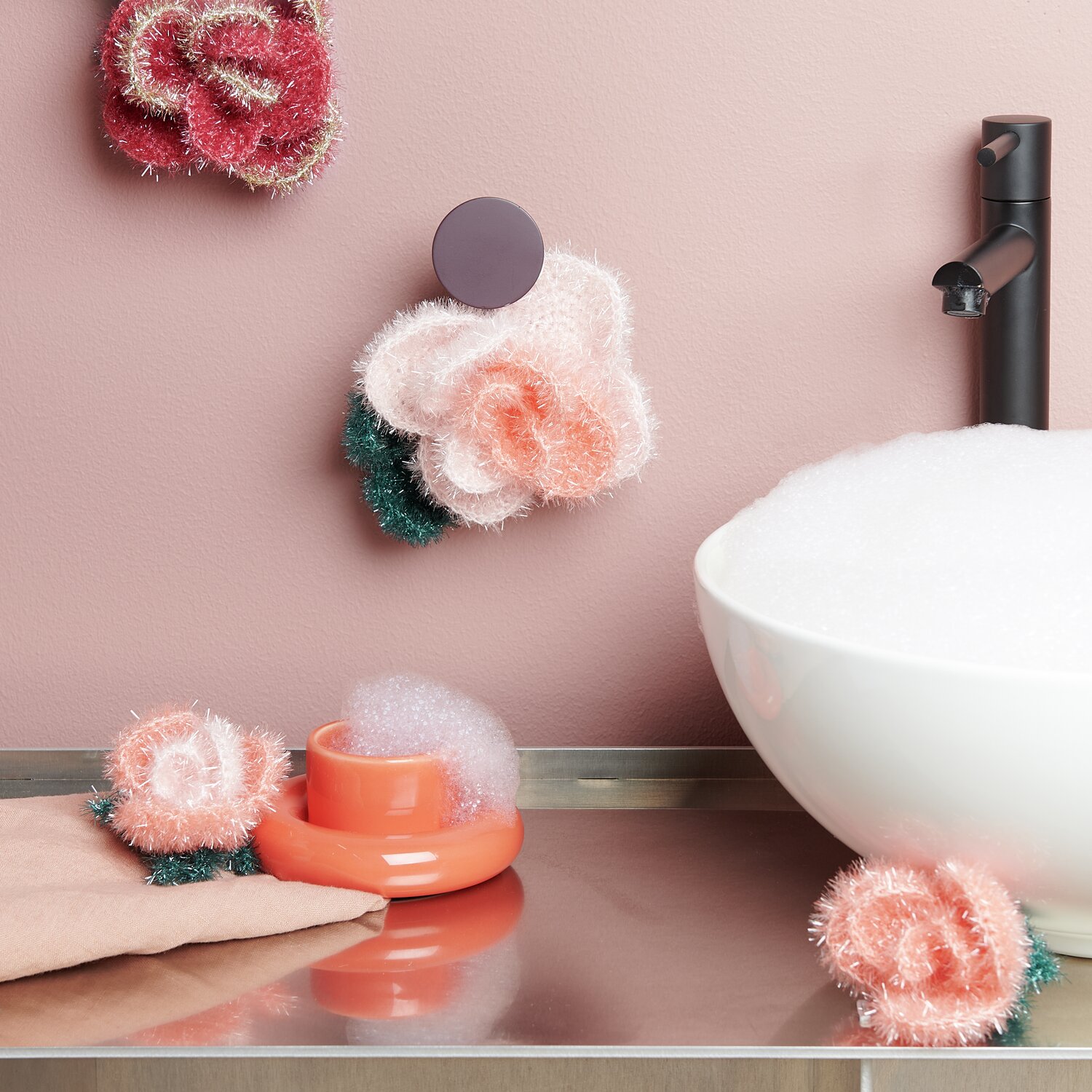 Häkelset Creative Bubble Rose Romantic von Rico Design Häkelset Creative Bubble Rose Romantic: Flauschige Rosen in Pastelltönen neben Waschbecken.