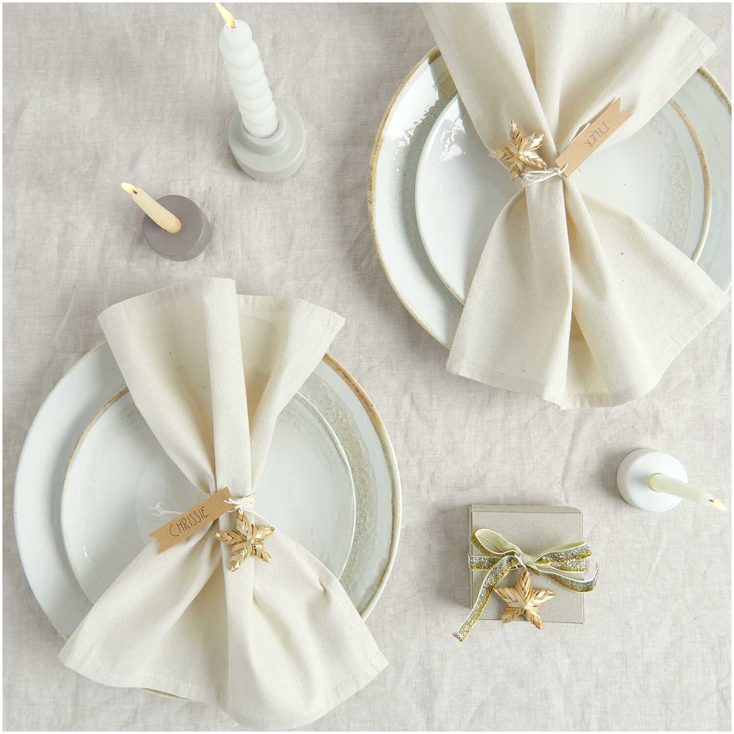 Stoffserviette 2 Stück natur Größe 30x30cm von Rico Design Stoffserviette 2 Stück natur von Rico Design auf elegant gedecktem Tisch mit Kerzen und Geschenkbox. Ideal für festliche Anlässe.