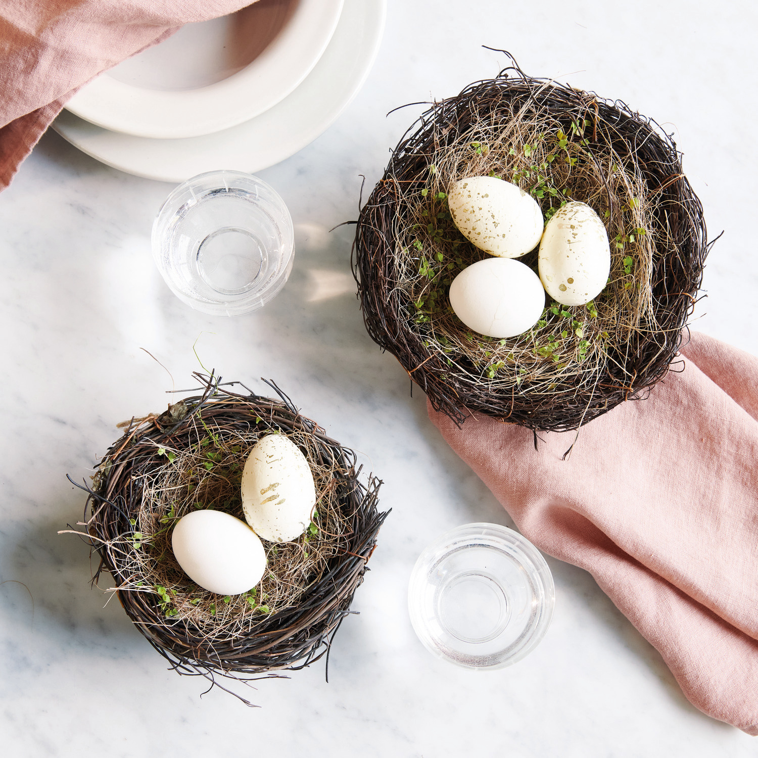 Eier creme-gold 6cm 6 Stück von Rico Design Naturnest mit Gras und creme-goldenen Eiern von Rico Design auf einem Tisch mit rosa Serviette.