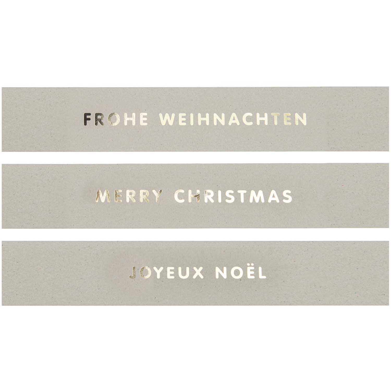 Paper Poetry Papierstreifen mit weihnachtlichen Grüßen in drei Sprachen auf grauem Hintergrund.