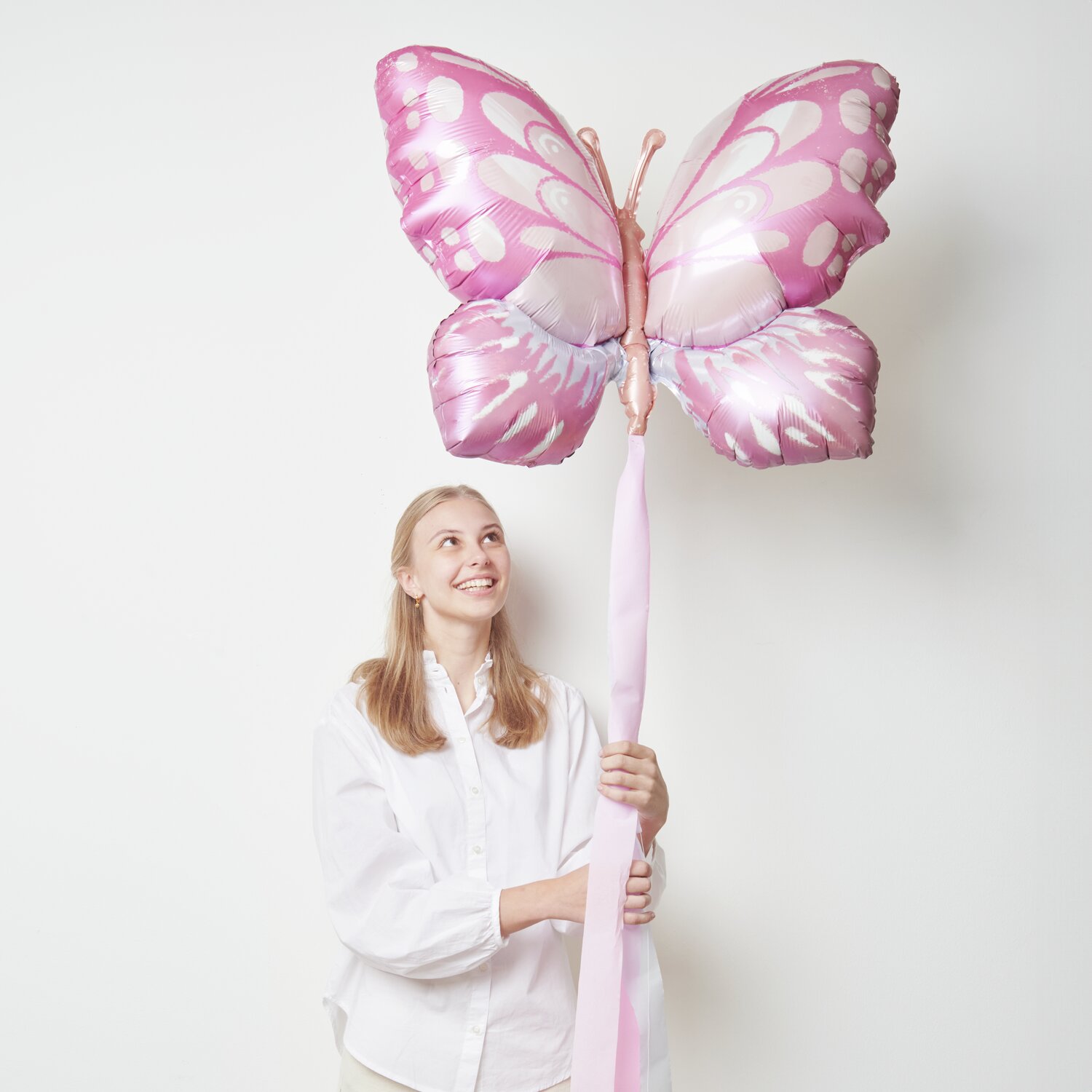 Folienballon Schmetterling Pink/Orange 77x57cm von Rico Design Folienballon Schmetterling Pink/Orange: Eine Person hält einen großen, pink-orangefarbenen Schmetterlingsballon von Rico Design.
