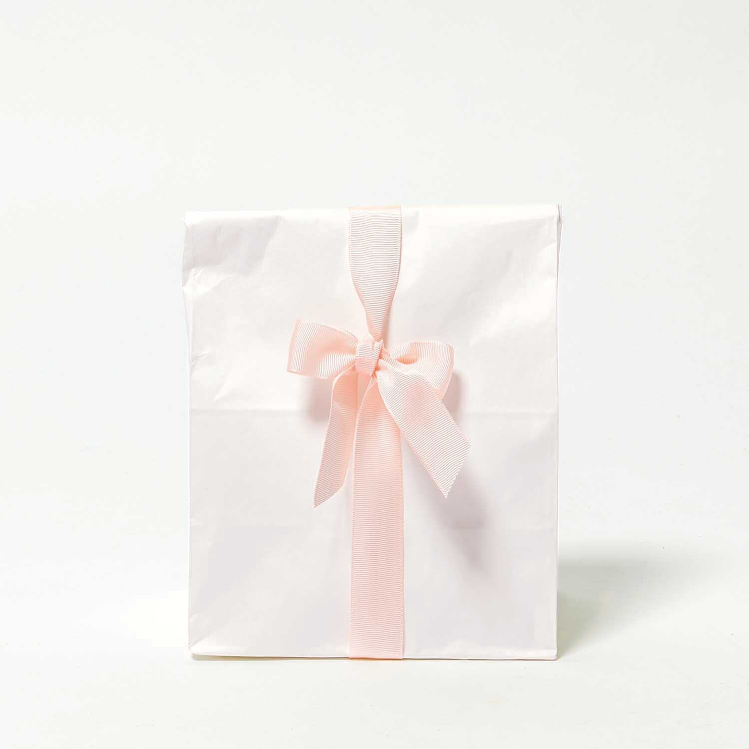 Paper Poetry Ripsband 25mm 3m Farbe rot von Rico Design Paper Poetry Ripsband, hellrosa, dekoriert eine weiße Geschenktüte mit einer eleganten Schleife.