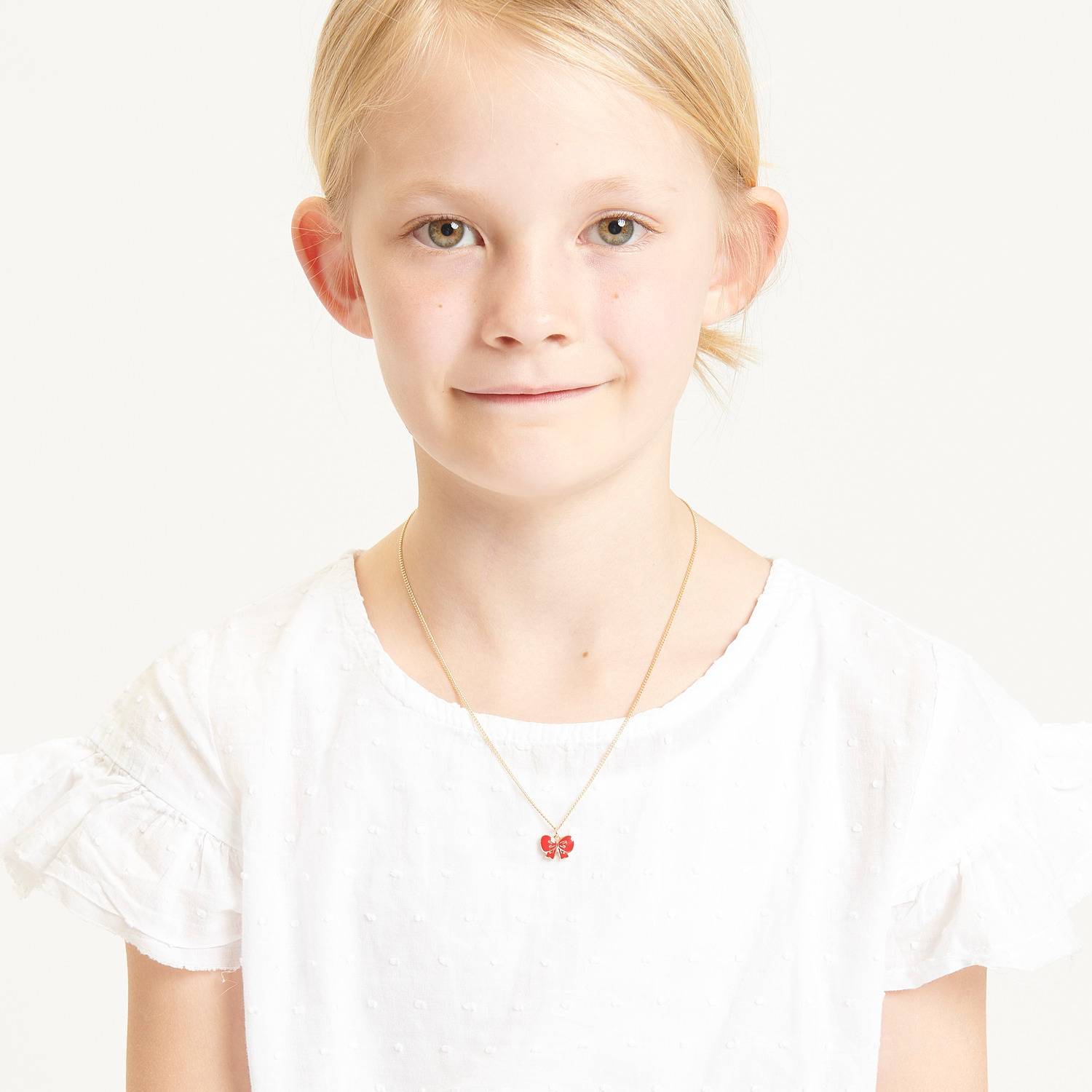 Kette mit Anhänger Schleife 40cm Farbe Rot von Rico Design Kette mit Anhänger Schleife, 40cm, von Rico Design. Mädchen trägt eine weiße Bluse.