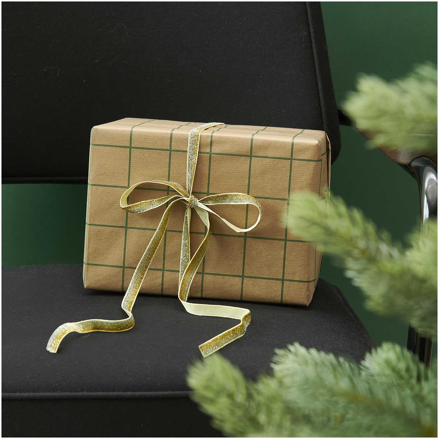 Paper Poetry Glitzerband 10mm 3m Farbe Silber-Gold von Rico Design Paper Poetry Glitzerband 10mm 3m: Ein Geschenk mit kariertem Papier und silber-goldenem Band auf einem Stuhl, umgeben von Tannenzweigen.