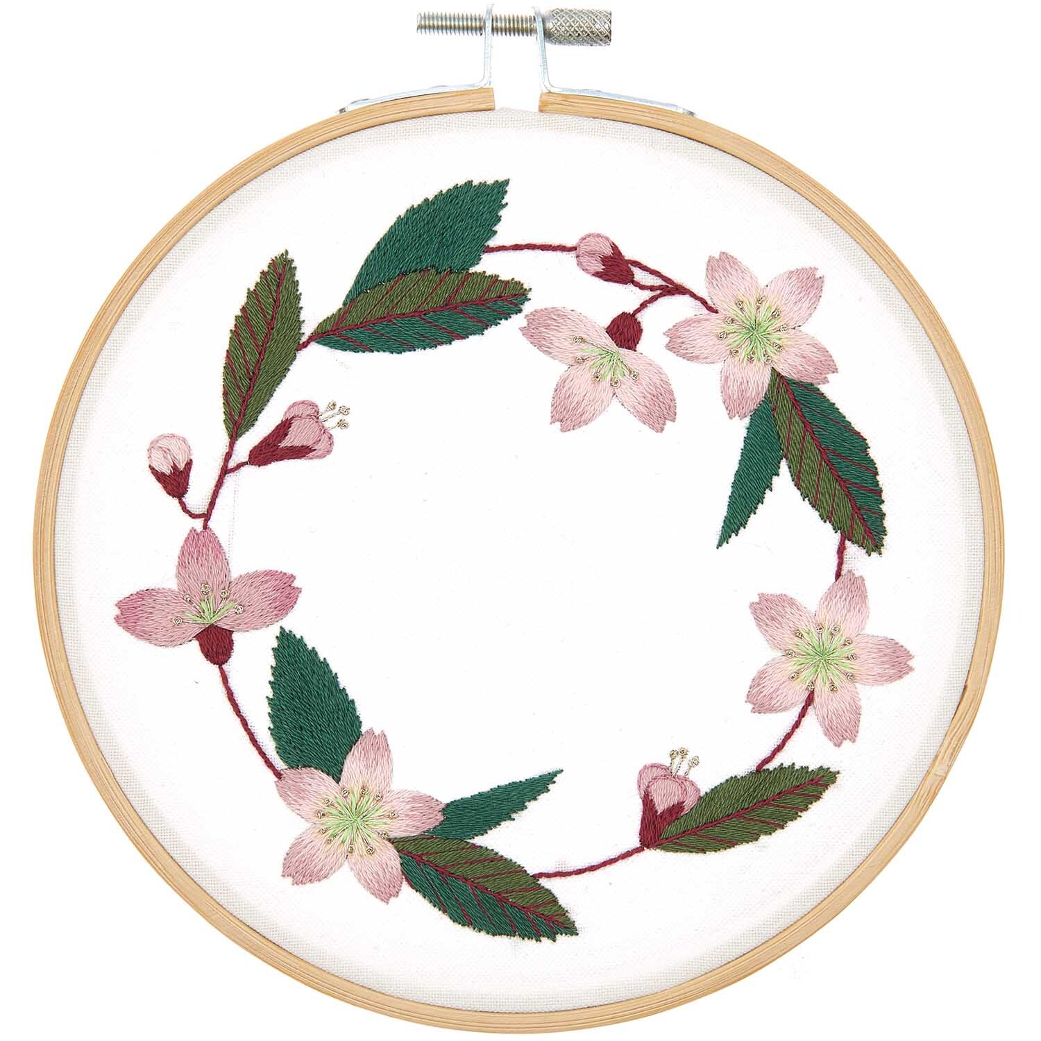 Stickpackung Kirschblütenkranz vorgezeichnet von Rico Design zeigt zarte rosa Blüten und grüne Blätter in einem Stickrahmen.