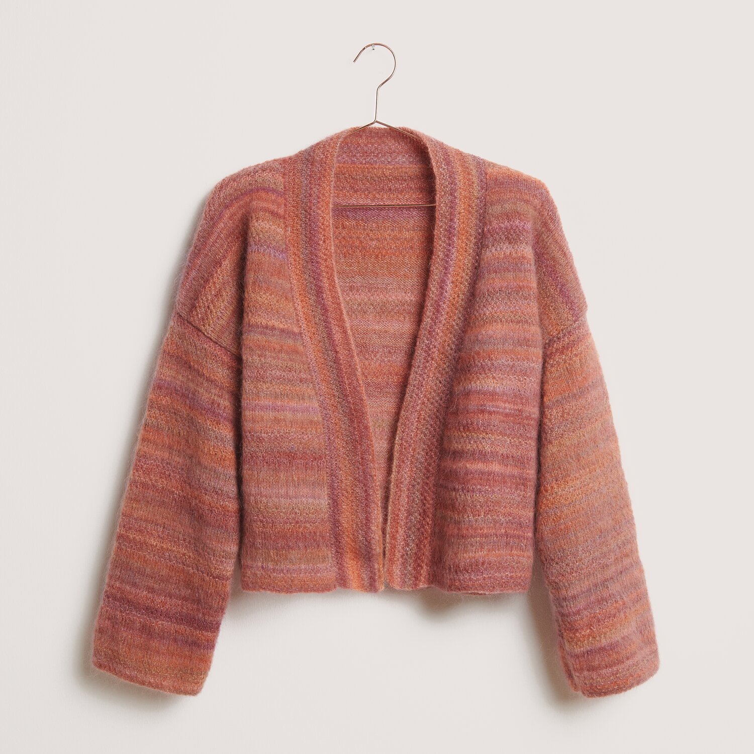 Fashion Meri Mohair Print 50g 275m Couleur Happy Sunrise from Rico Design Strickset Kimono-Jacke Modell 01 in warmen Rottönen, präsentiert auf einem Kleiderbügel. Ideal für den Winter.