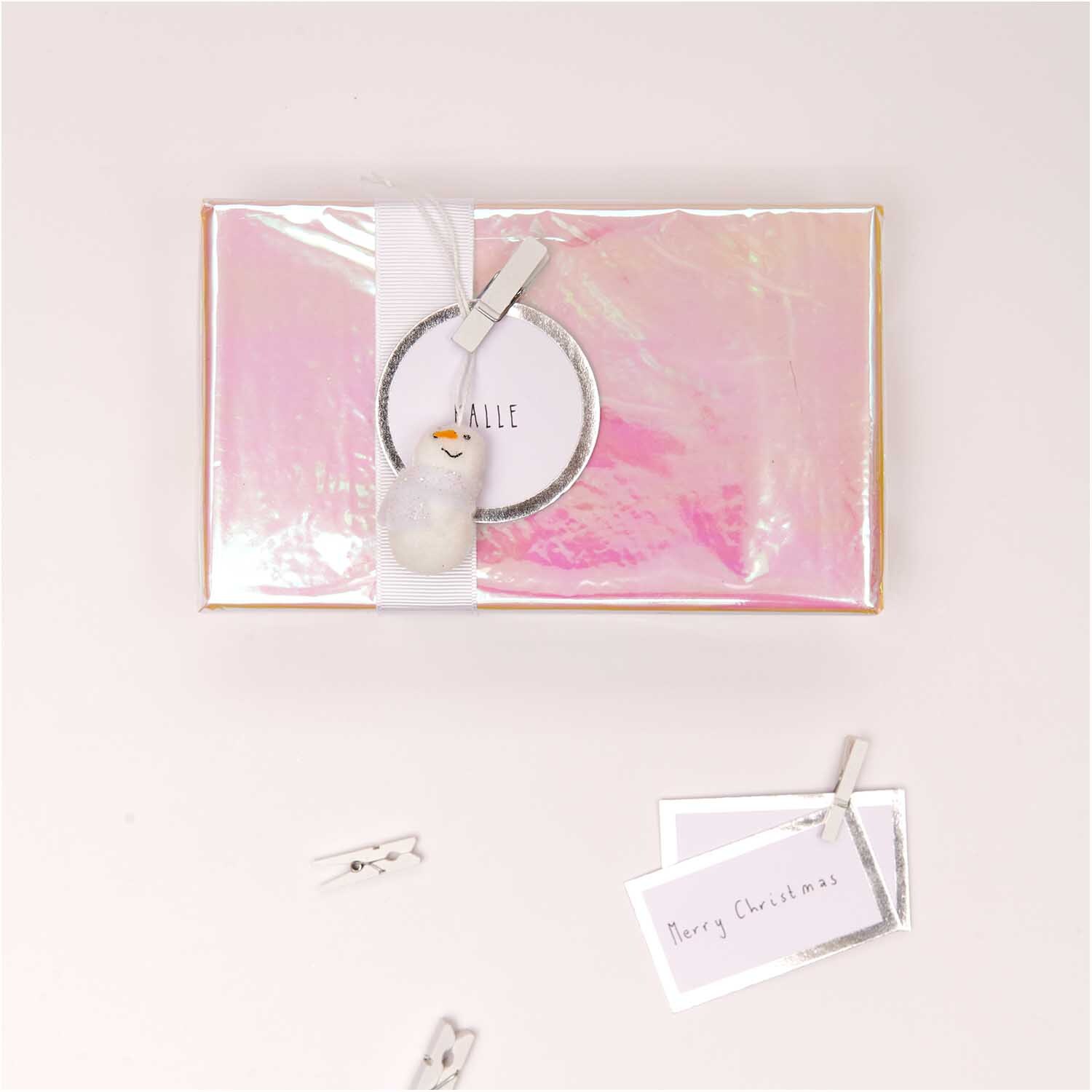 Holzklammern weiß 3,5cm 12 Stück von Rico Design Holzklammern weiß 3,5cm 12 Stück von Rico Design auf einem rosa Geschenk mit Karte und Dekoration.