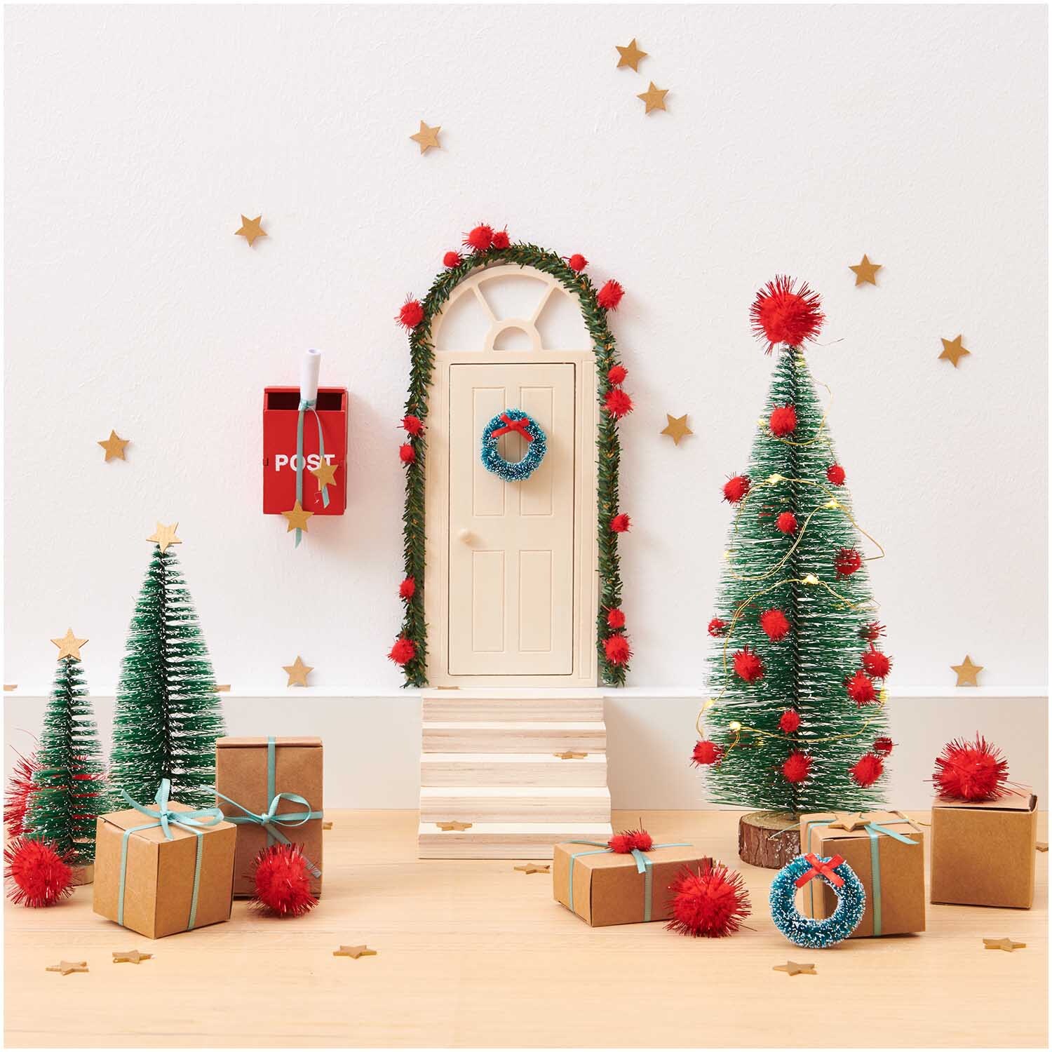 Miniatur Wichteltür mit Bogen, umgeben von festlichen Dekorationen wie Bäumen und Geschenken.