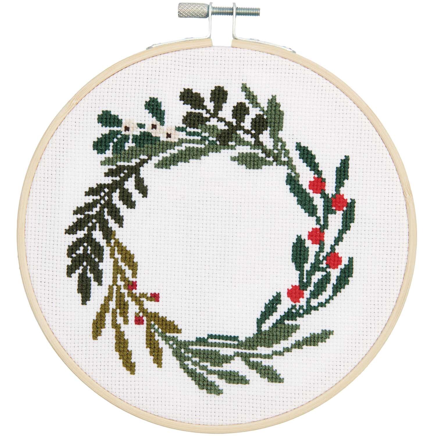 Stickpackung Beerenkranz Bild Ø 15cm zeigt einen grünen Kranz mit roten Beeren auf weißem Stoff. Marke: Rico Design.