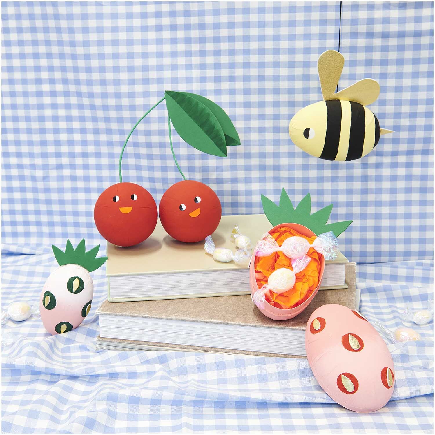 Pappmaché Kugel weiß 8cm von Rico Design auf kariertem Hintergrund mit bunten Dekorationen.