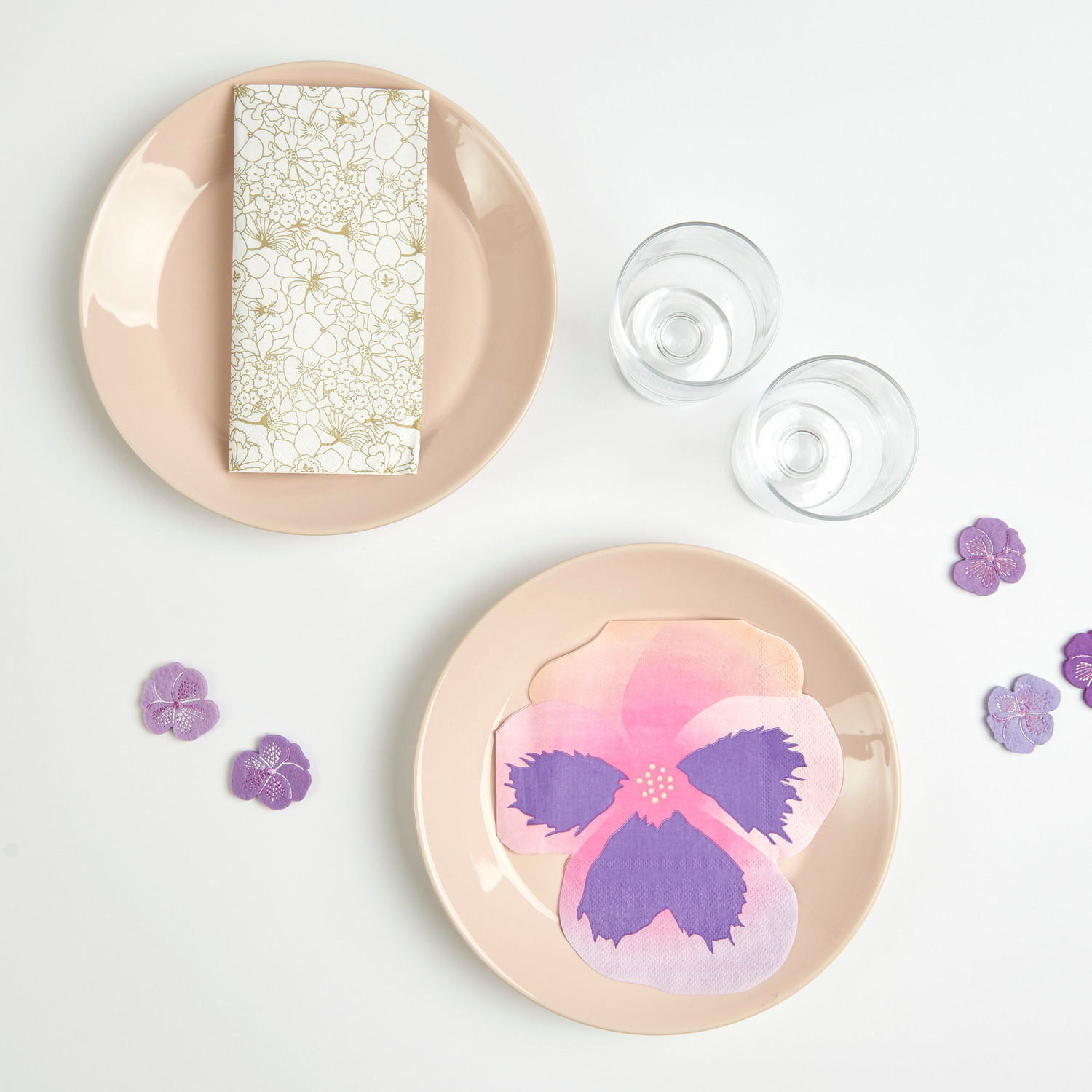 Servietten Stiefmütterchen 30x32cm 20 Stück von Rico Design Filzstreu Stiefmütterchen bestickt Violett: Zwei Teller mit Servietten und violetten Blüten, ideal für elegante Tischdekoration.