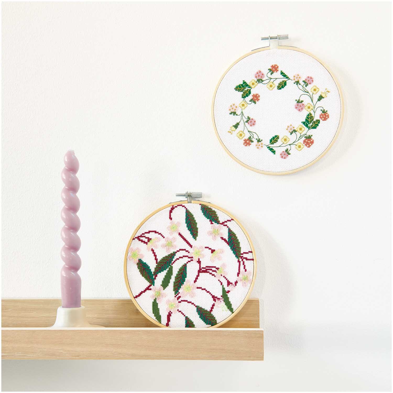 Pack de broderie Image Fleurs de cerisier Ø15cm from Rico Design Stickpackung Bild Kirschblüten zeigt zwei runde Stickrahmen mit floralen Designs an einer Wand.
