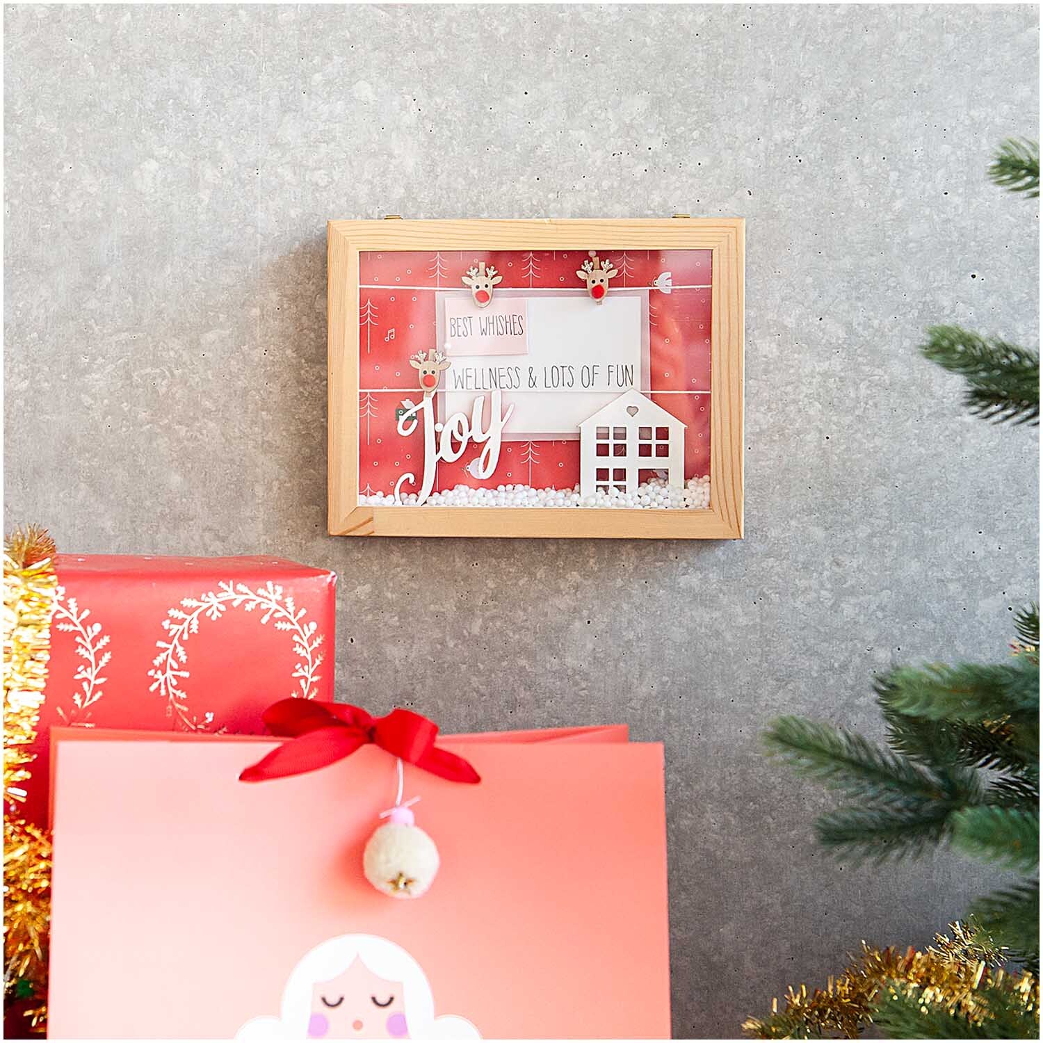Holzdeko-Set Berglandschaft für XL-Dekohaube 6-teilig von Rico Design Holzdeko-Set Berglandschaft für XL-Dekohaube: Weihnachtliche Szene in Holzrahmen, umgeben von roten Geschenken und Tannenzweigen.
