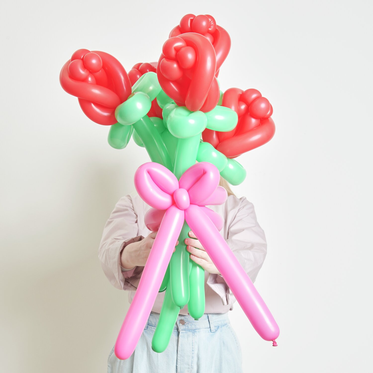 Ballonstrauß Rosen Rot 60cm 12 Stück von Rico Design Ballonstrauß Rosen Rot von Rico Design: Ein Strauß aus roten und grünen Ballons, kunstvoll gebunden, gehalten von einer Person.