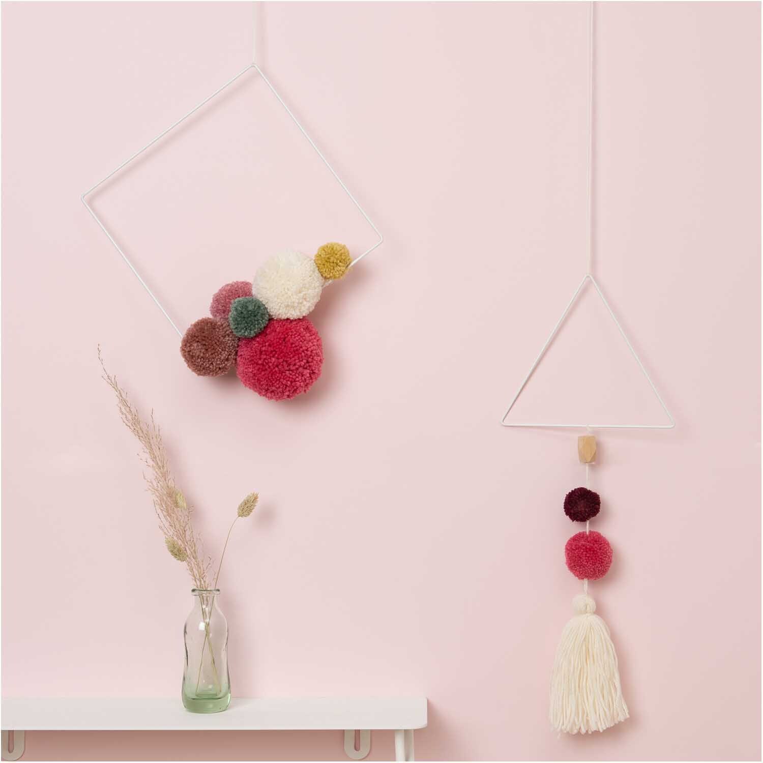 Metallring Quadrat weiß Größe 30cm von Rico Design Metallring Quadrat weiß von Rico Design mit bunten Pompons, dekorativ an einer rosa Wand hängend.