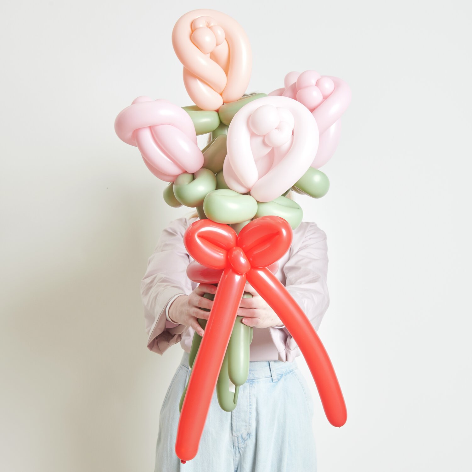 Ballonstrauß Rosen Rosa Mix 60cm 12 Stück von Rico Design Ballonstrauß Rosen Rosa Mix: Ein Strauß aus rosa und grünen Ballons, kunstvoll gebunden, mit roter Schleife.