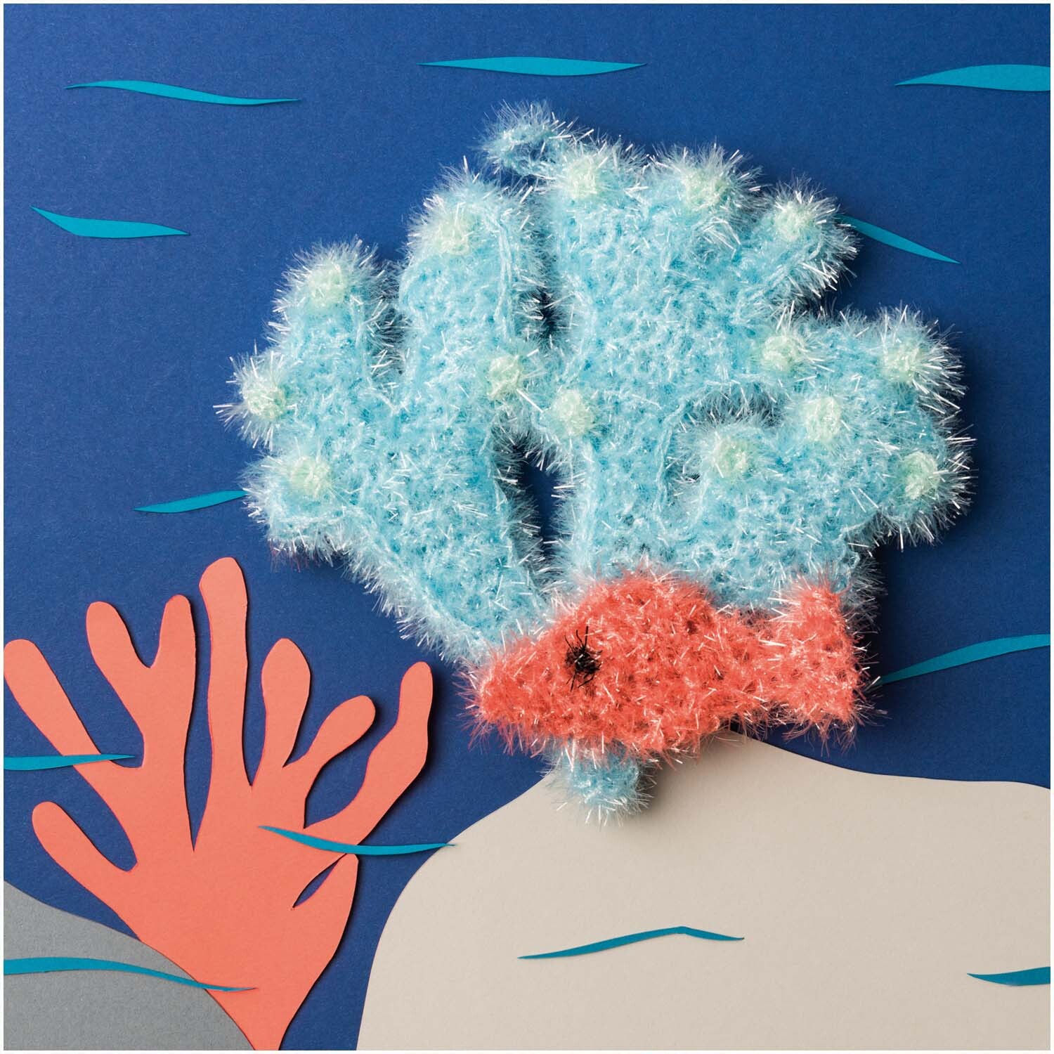 Creative Bubble - Beyond the Sea: Häkeldesign von Rico Design mit blauem Korallenriff und rotem Fisch.