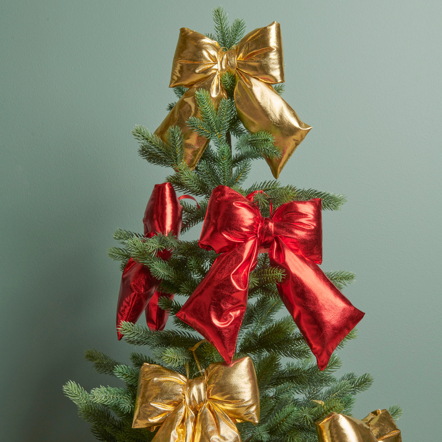 Weihnachtsschleife Gold Größe 24x19x5cm von Rico Design Weihnachtsschleife Gold: Festliche Schleifen in Gold und Rot schmücken einen grünen Tannenbaum.