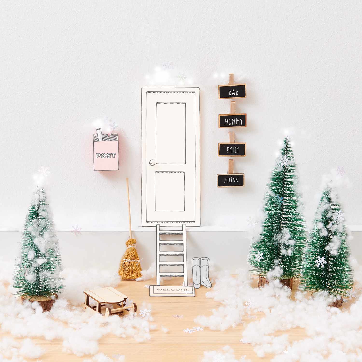 Wichtelwelt Deko Set Schnee von Rico Design zeigt eine Miniatur-Winterlandschaft mit Tannenbäumen, Tür und Schlitten.