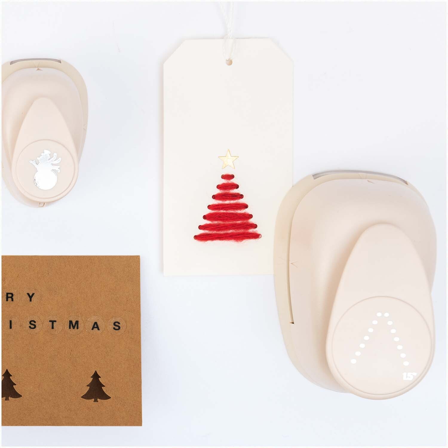 Paper Poetry Stanzer DIY-Tanne 3,8cm von Rico Design Paper Poetry Stanzer DIY-Tanne 3,8cm von Rico Design neben einer Karte mit rotem Tannenbaum und Weihnachtsmotiv.