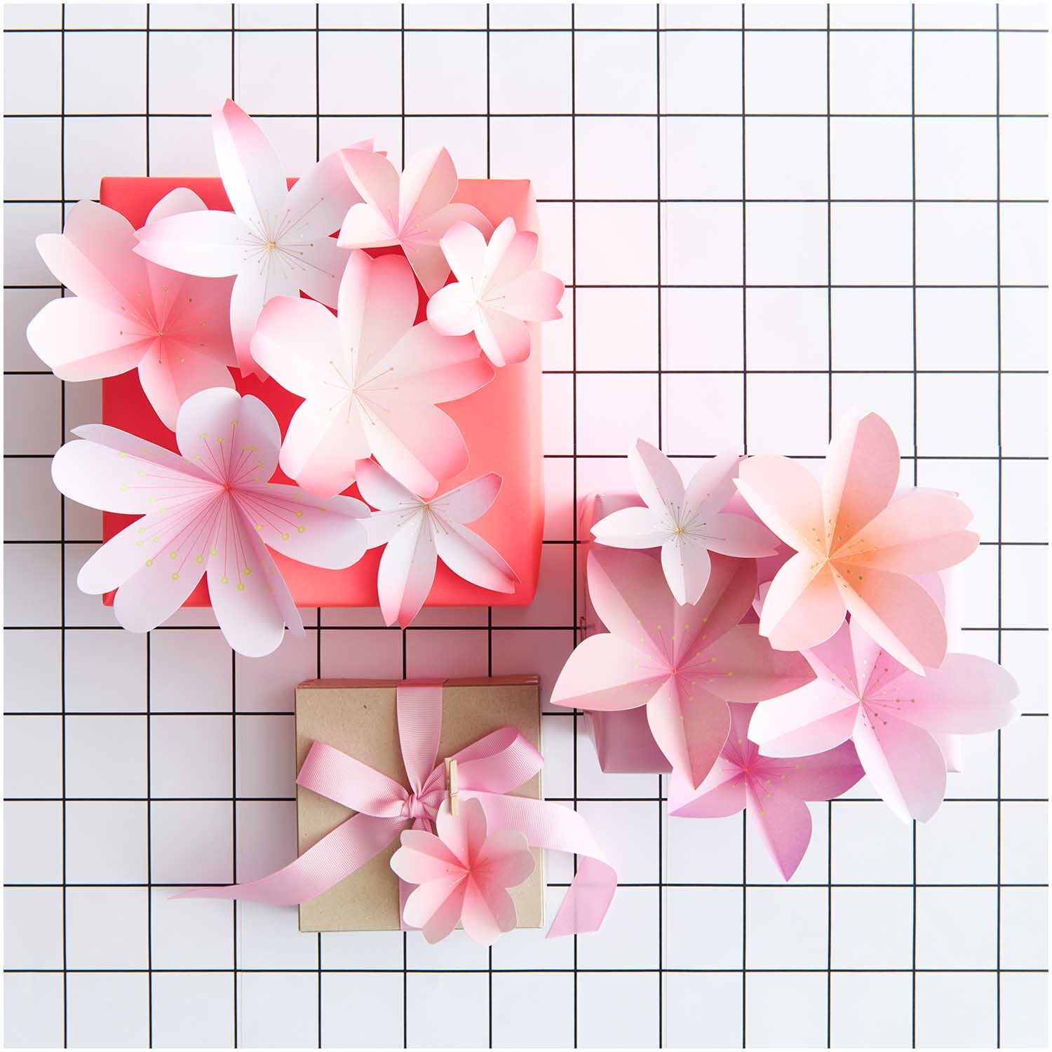Paper Poetry Mini-Papierblüten in Rosa auf kariertem Hintergrund, dekorativ arrangiert. Ideal für kreative Projekte von Rico Design.