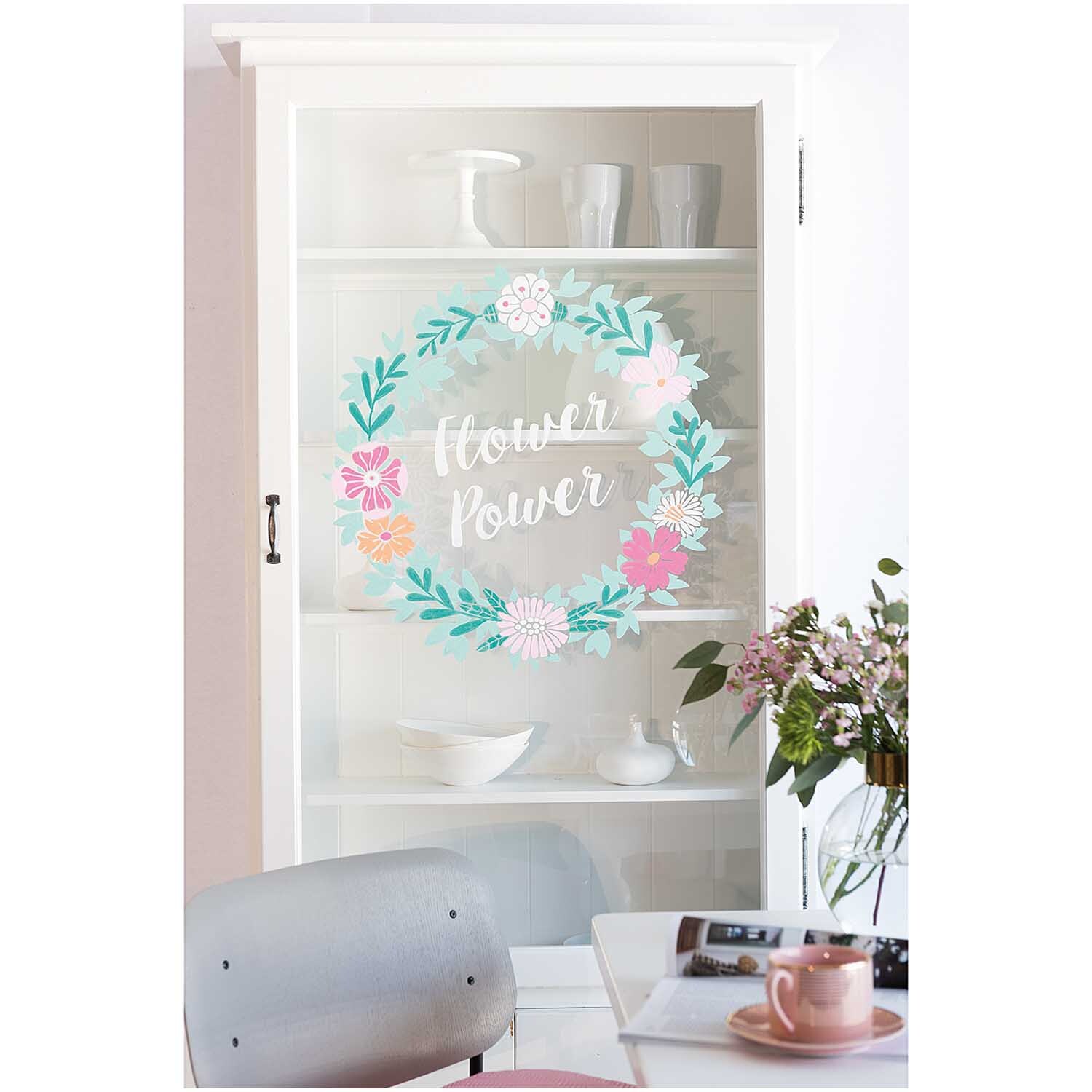 Vorlagenmappe Flowers and Plants Fenster- und Glasmalerei mit Kreidestiften von Rico Design Vorlagenmappe Flowers and Plants: Ein weißer Schrank mit Blumenkranz und Schriftzug "Flower Power" auf der Glastür, dekoriert mit Geschirr.