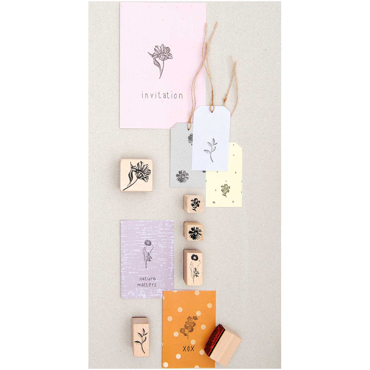 Paper Poetry Stempelset Blumen, 7-teilig, zeigt florale Designs auf Karten in Pastellfarben. Ideal für kreative Bastelprojekte und Einladungen.