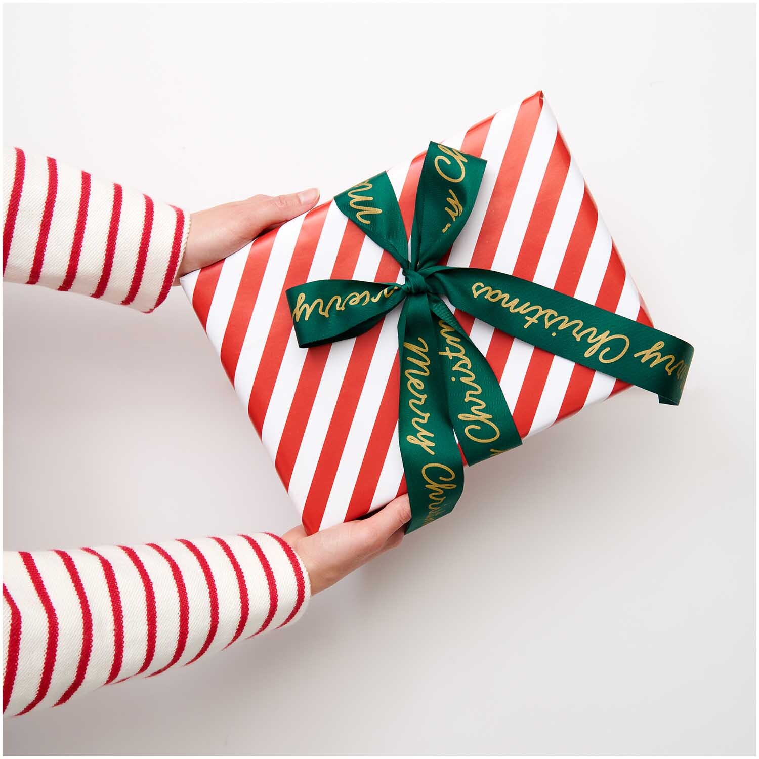 Paper Poetry Taftband Merry Christmas grün 38mm 3m von Rico Design Paper Poetry Taftband Merry Christmas: Ein Geschenk mit rot-weißem Streifenpapier und grünem Band von Rico Design.