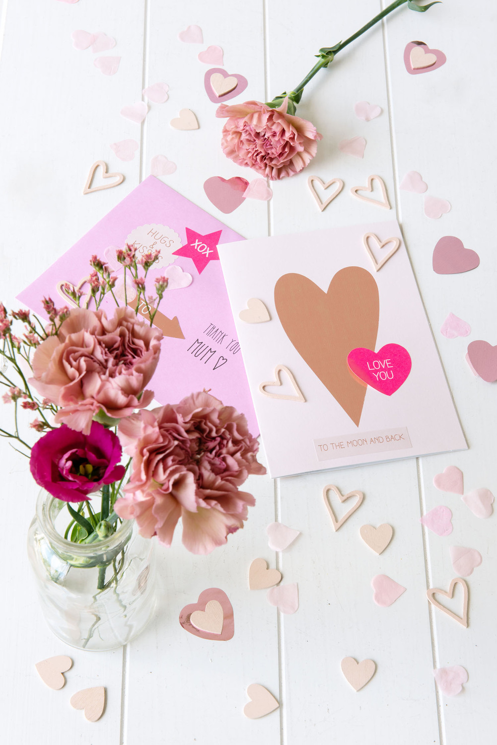 Paper Poetry Grußkartenset It must be love Herz pink von Rico Design Paper Poetry Grußkartenset mit Herzmotiv und Blumen auf weißem Tisch, umgeben von rosa Herzen.