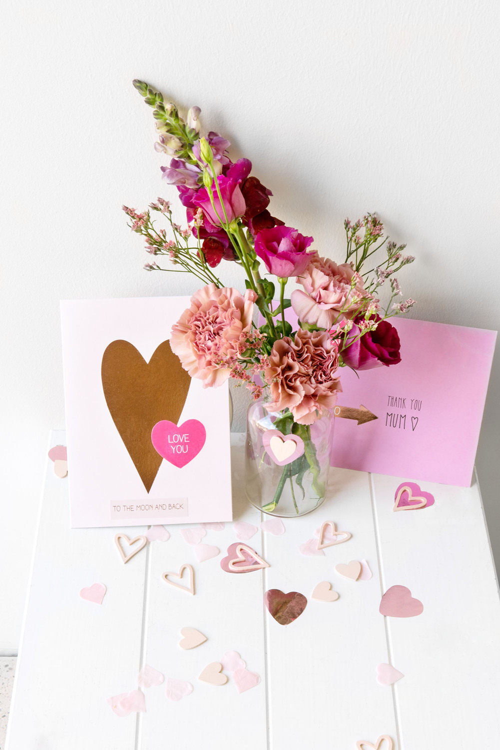 Paper Poetry Grußkartenset It must be love Herz pink von Rico Design Paper Poetry Grußkartenset mit Herzmotiv in Pink, neben einem Blumenstrauß auf weißem Tisch arrangiert.