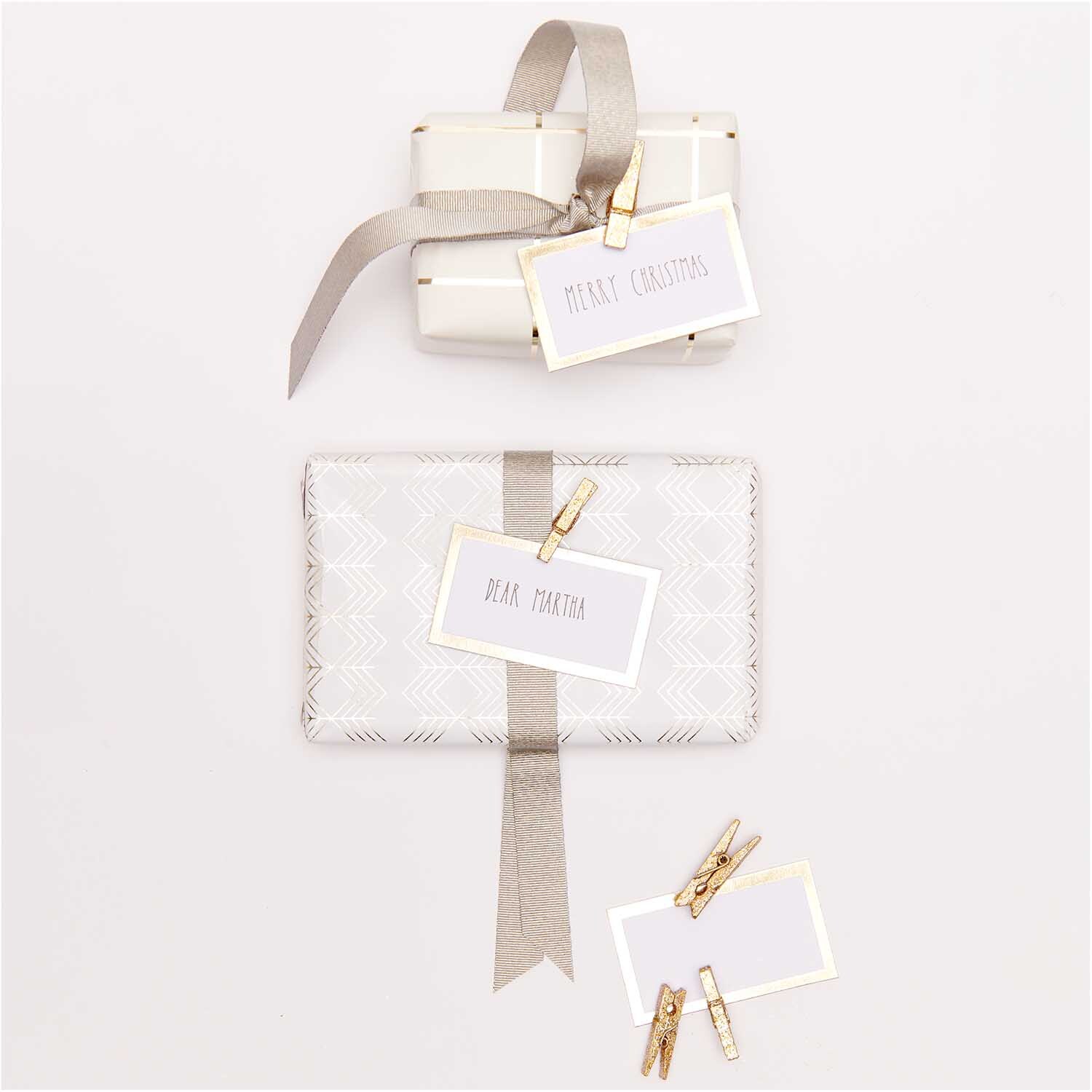 Paper Poetry Papierkärtchen mit Hot Foil, dekoriert auf Geschenken mit goldenen Klammern und Schleifen. Elegantes Design von Rico Design.