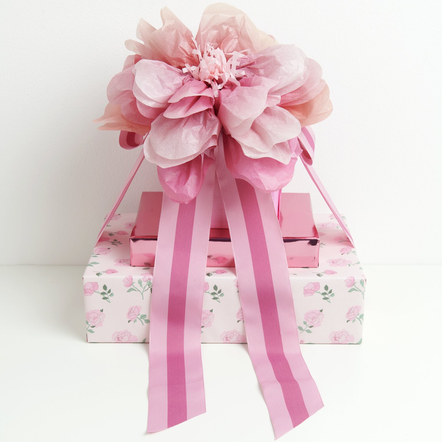 Seidenpapierblumen Wildrose Rosa von Rico Design: Drei zarte Blumen auf Geschenkbox mit rosa Schleifen.