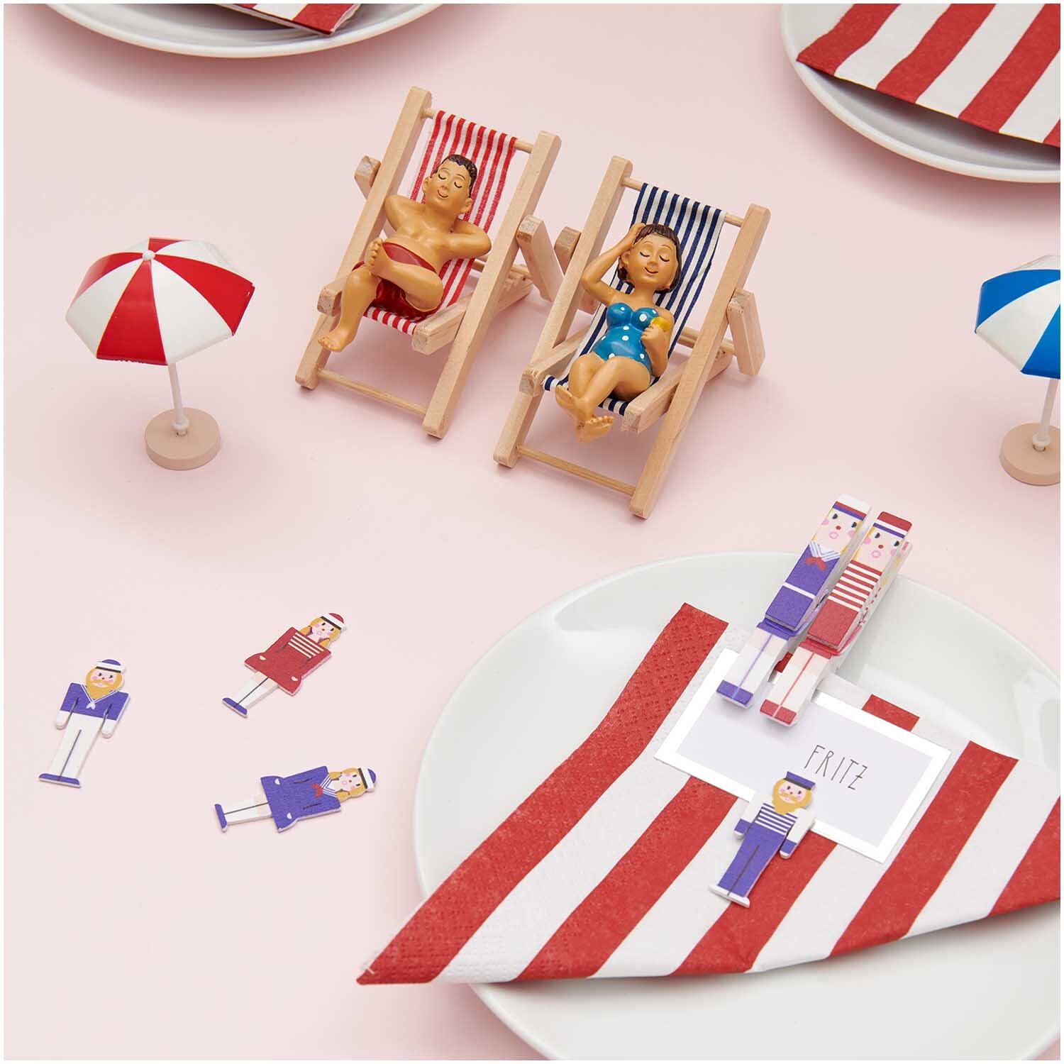 Figurine de décoration Vacancier 8x5cm from Rico Design Deko-Figur Urlauber 8x5cm: Zwei Miniatur-Urlauber in Liegestühlen mit rot-weiß gestreiften Handtüchern und kleinen Sonnenschirmen.