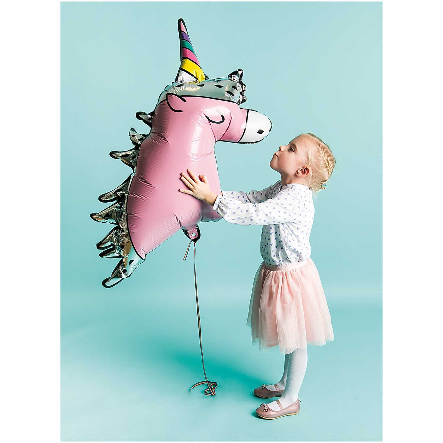 Folienballon Einhorn 85x83cm von Rico Design Folienballon Einhorn 85x83cm: Ein Mädchen umarmt einen rosa Einhornballon von Rico Design vor blauem Hintergrund.