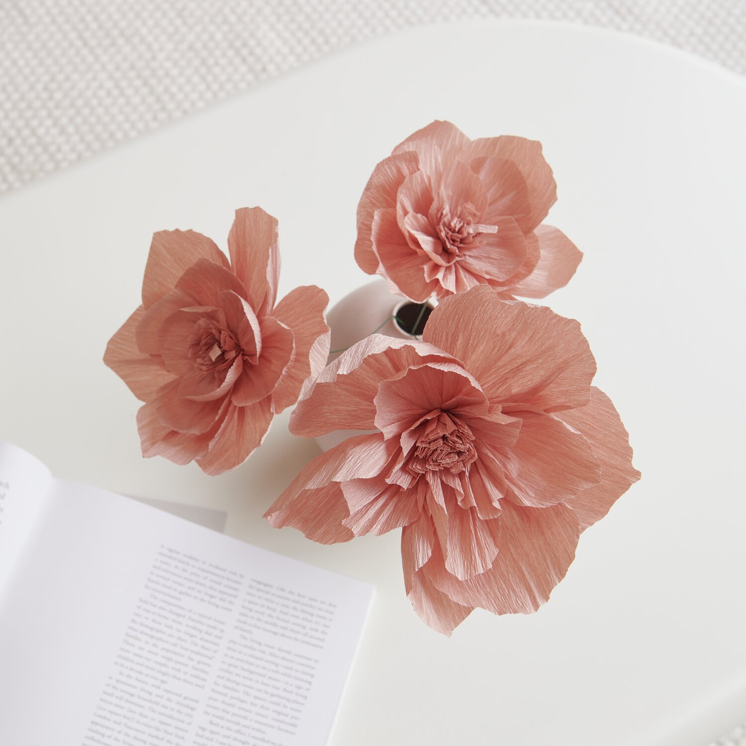 Krepppapier Blüten in Terracotta von Rico Design, kunstvoll arrangiert in einer Vase auf einem Tisch.