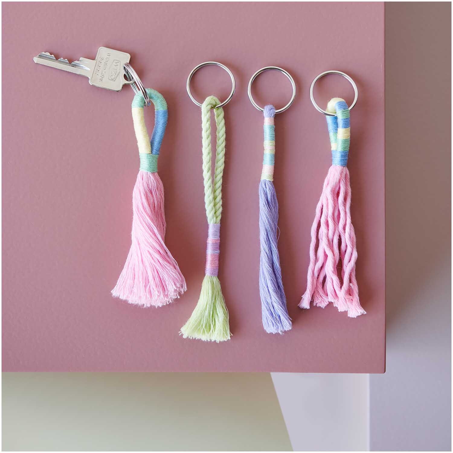 Set de fils à broder Ice Cream 10 pièces 10-teilig from Rico Design Stickgarn Set Ice Cream: Vier bunte Schlüsselanhänger aus mehrfarbigem Garn von Rico Design, dekorativ arrangiert.