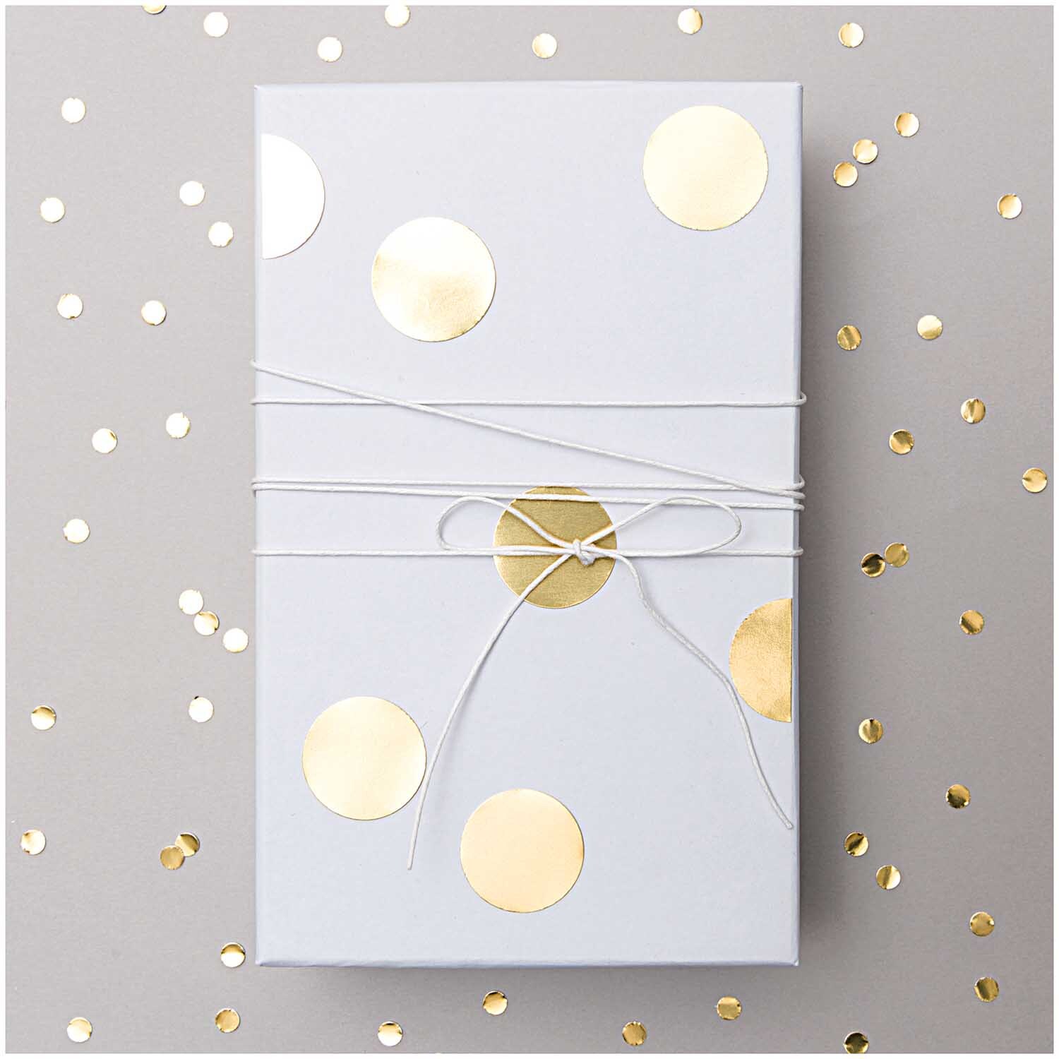 Paper Poetry Sticker Punkte gold 15mm 4 Bogen von Rico Design Paper Poetry Sticker Punkte gold 15mm 4 Bogen auf Geschenkverpackung mit goldenen Punkten dekoriert.