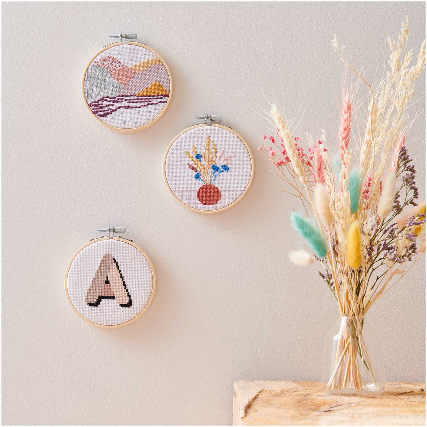 Kit de broderie Mini Kit Alphabet Image Ø 10cm from Rico Design Stickpackung Mini Kit Alphabet Bild Ø 10cm: Drei runde Stickrahmen an der Wand, daneben bunte Trockenblumen in Vase.