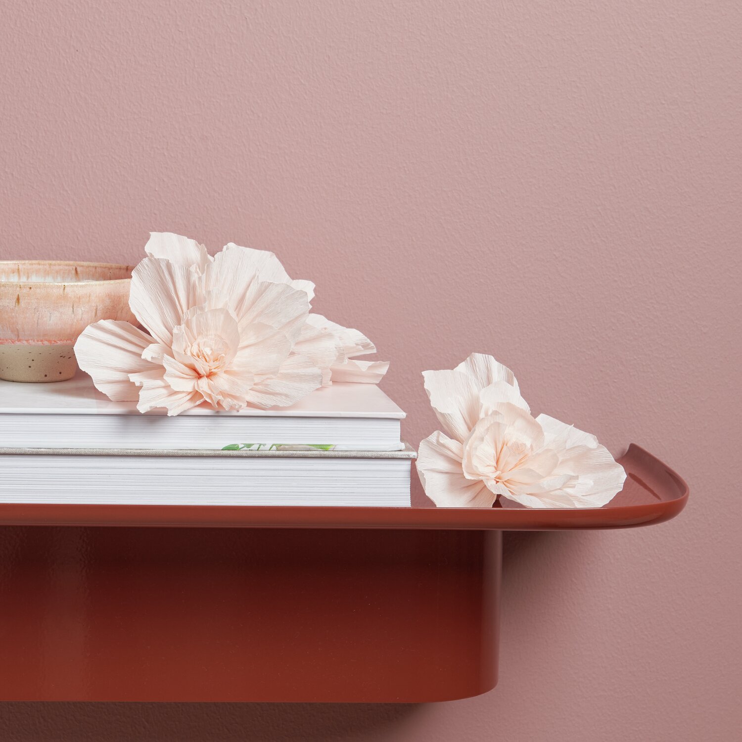 Krepppapier Blüten 3 Stück Farbe Soft Pfirsich von Rico Design Krepppapier Blüten, Soft Pfirsich, 3 Stück, dekorativ auf einem roten Regal neben Büchern arrangiert.