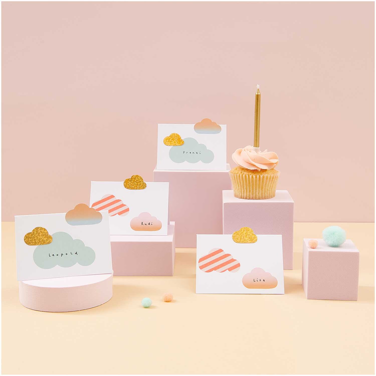 Paper Poetry Tischkarten Wolken 9x12,6cm 8 Stück von Rico Design Paper Poetry Tischkarten mit Wolkenmotiv und pastellfarbenen Details, dekorativ arrangiert neben einem Cupcake. Ideal für festliche Anlässe.