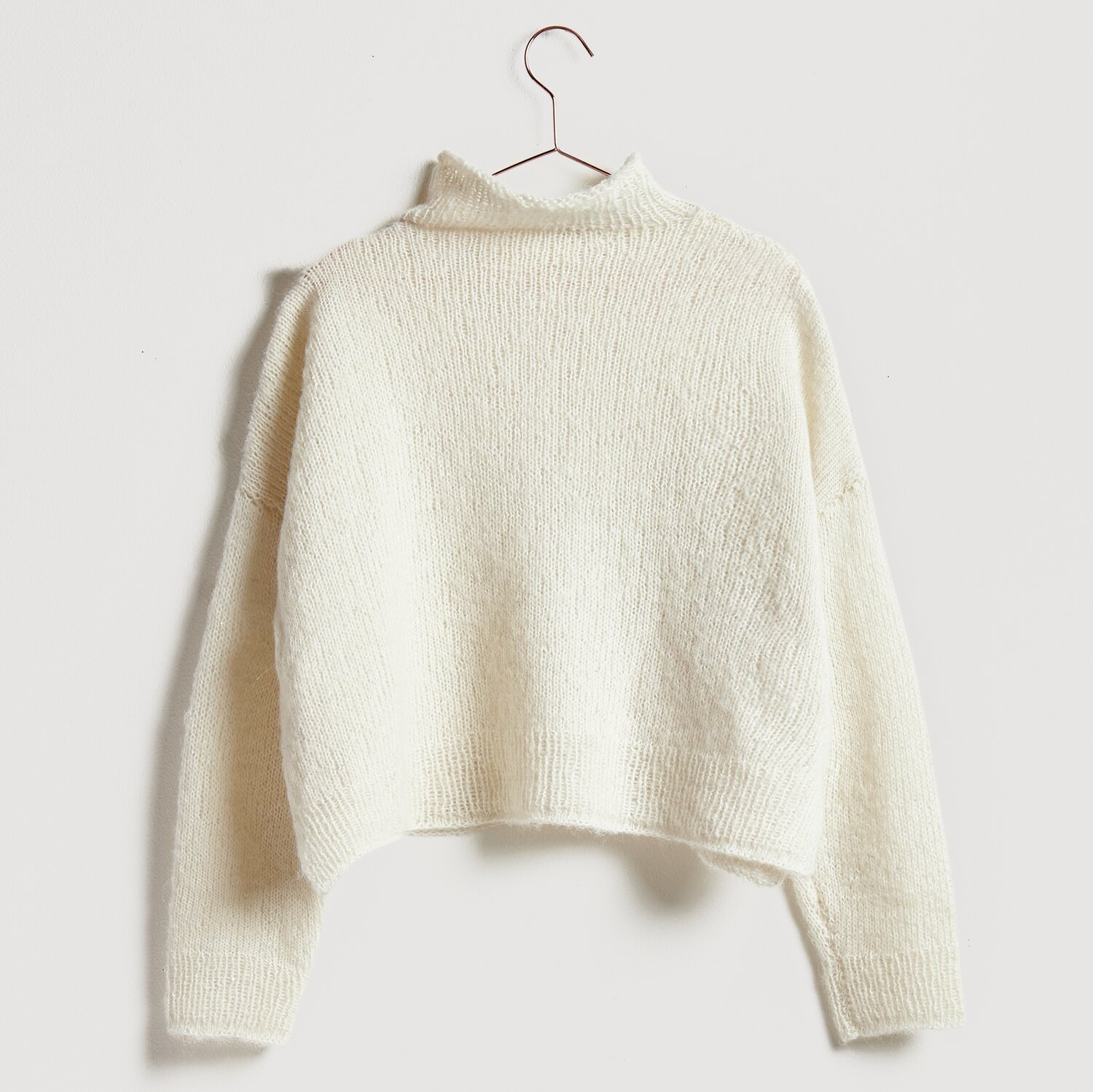 Luxury Alpaca Cotton Fusion 50g 190m Farbe Creme von Rico Design Luxury Alpaca Cotton Fusion Pullover in Creme, gestrickt aus weicher Wolle, hängt an einem Kleiderbügel.