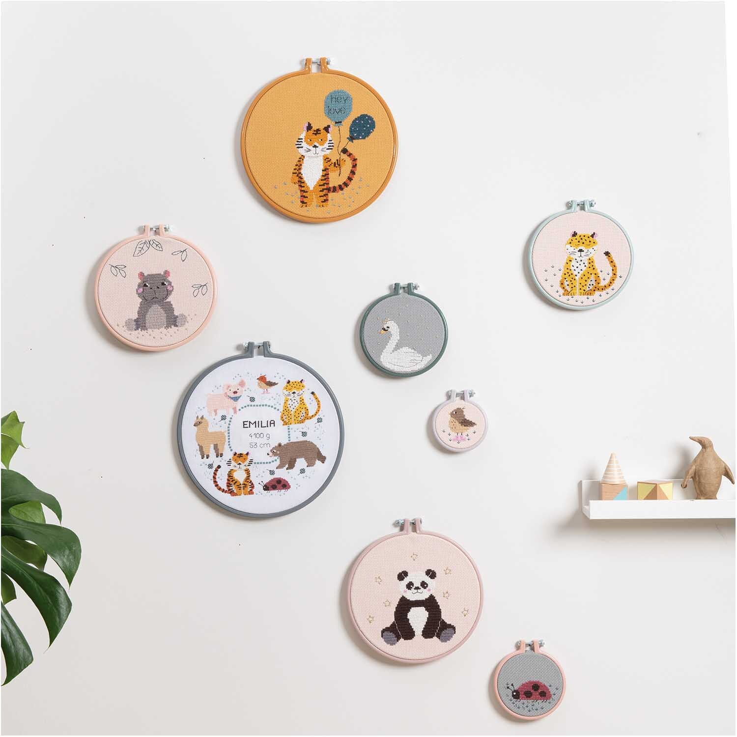 Paquet à broder Image de naissance animaux from Rico Design Stickpackung Geburtsbild Tiere: Wand mit bunten Stickrahmen von Rico Design, die verschiedene Tiermotive zeigen.