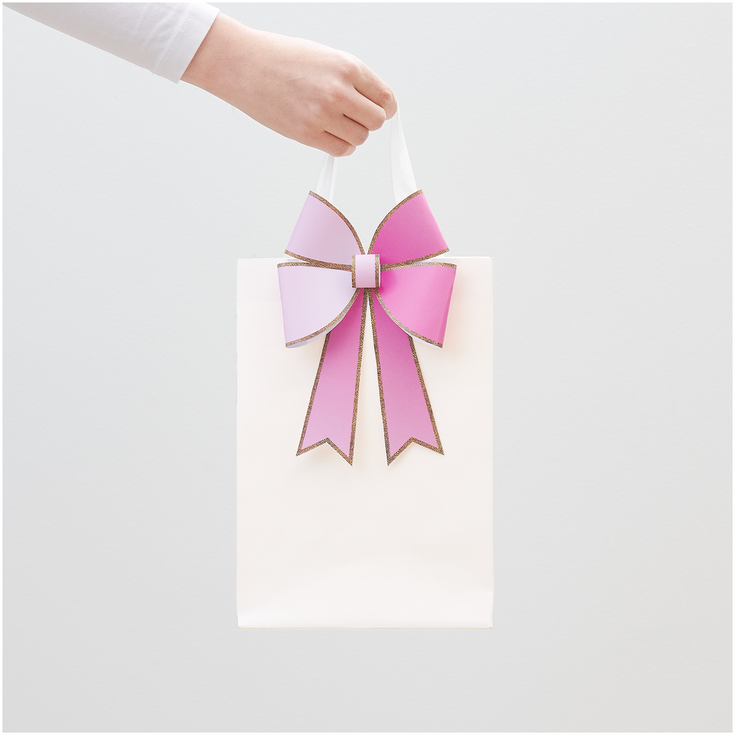 Paper Poetry bloc de papier de bricolage Put a Bow on it 12 feuilles from Rico Design Paper Poetry Bastelpapierblock Put a Bow on It: Hand hält weiße Tasche mit rosa Schleife, 12 Blatt von Rico Design.