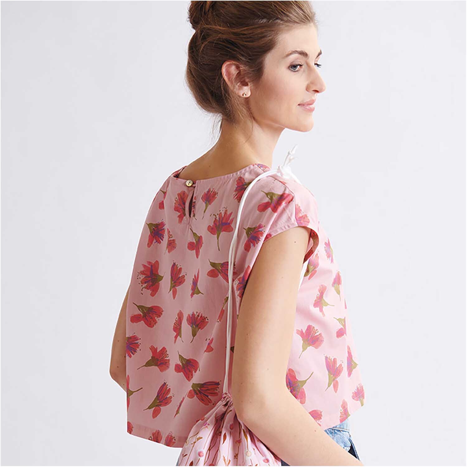 Meterware Druckstoff Aquarellblüten lachs von Rico Design Meterware Druckstoff Aquarellblüten lachs: Frau trägt ein lachsfarbenes Oberteil mit floralen Aquarellblüten von Rico Design.