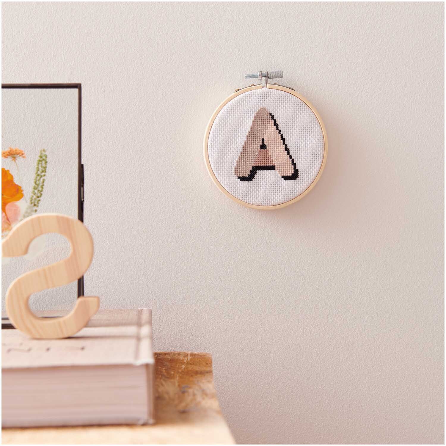 Kit de broderie Mini Kit Alphabet Image Ø 10cm from Rico Design Stickpackung Mini Kit Alphabet Bild Ø 10cm zeigt ein gesticktes A in Holzrahmen an einer Wand.
